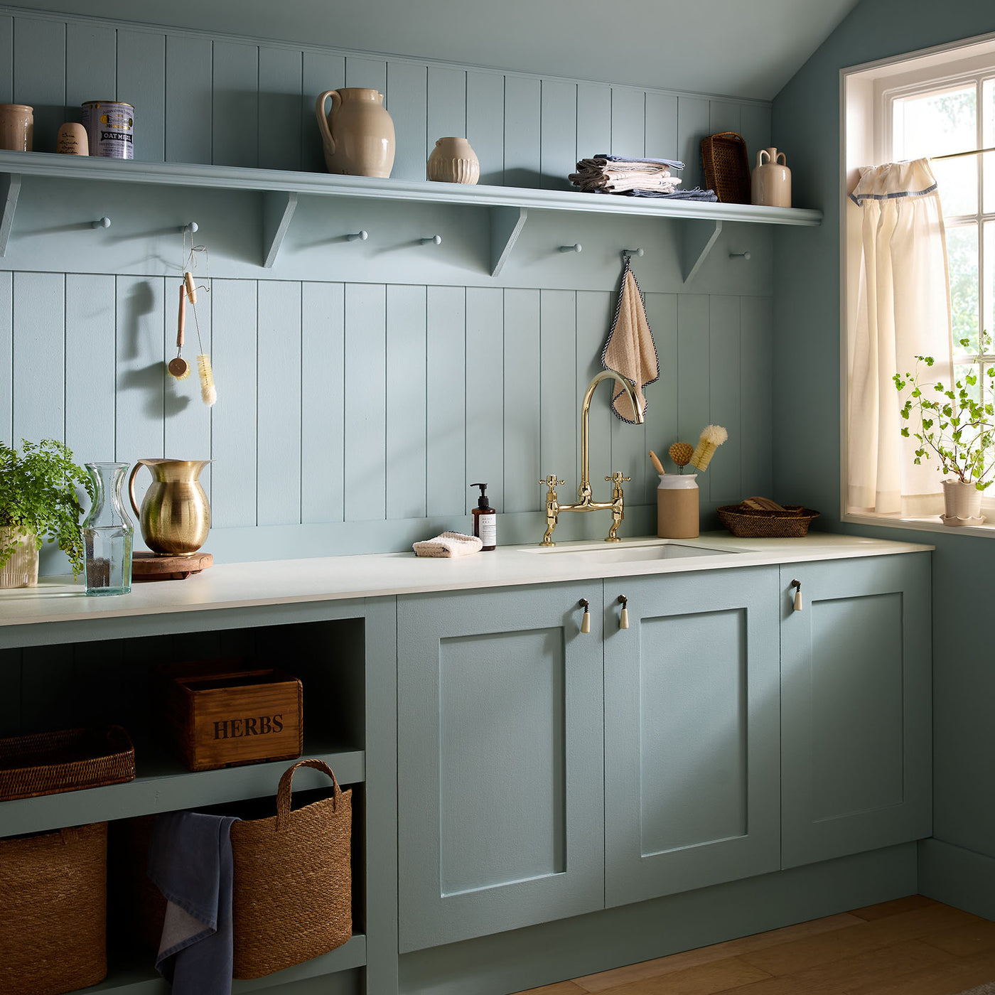 Modern kitchen with light blue cabinets, white countertops, and decorative items.