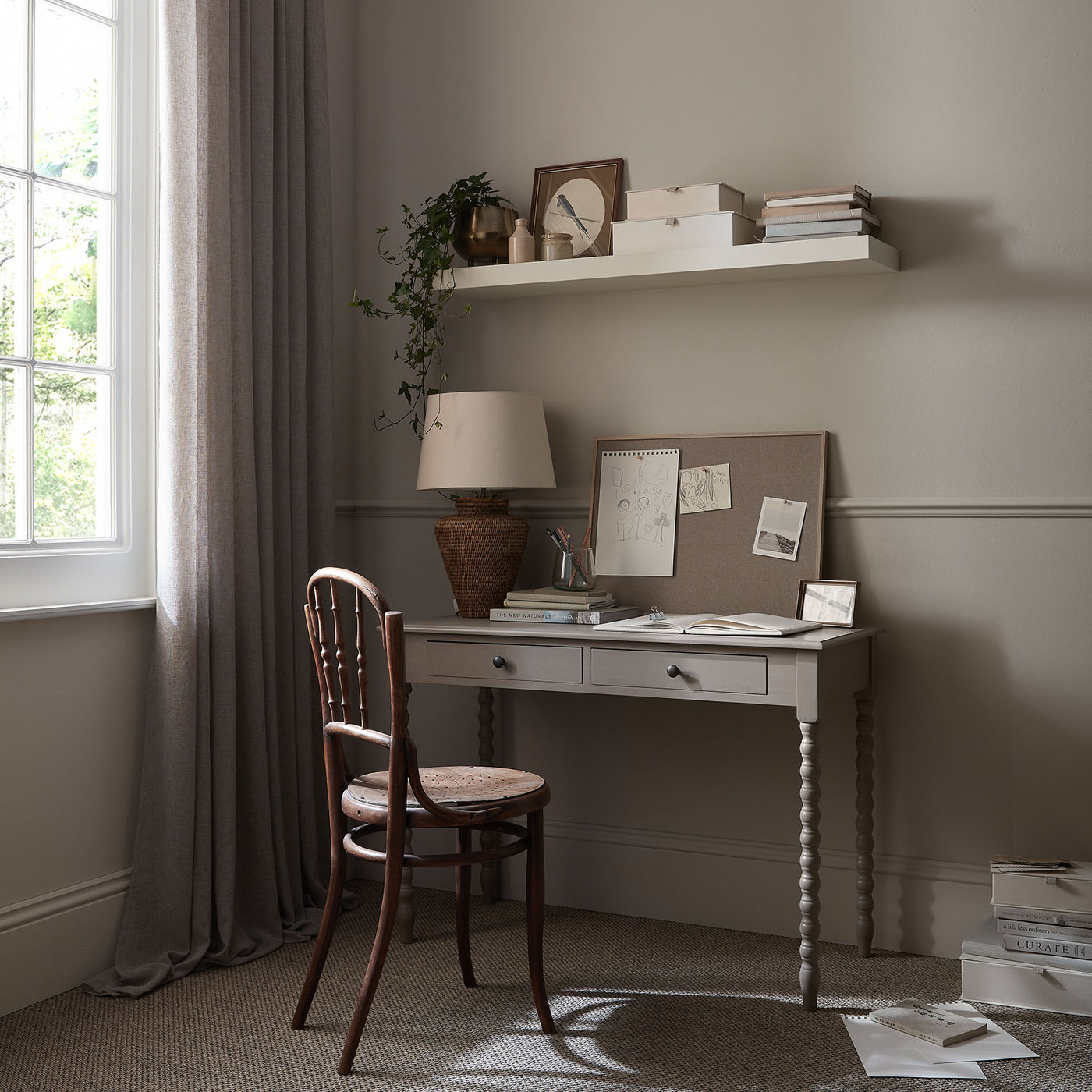 Home office with a desk, chair, and shelves against a wall.