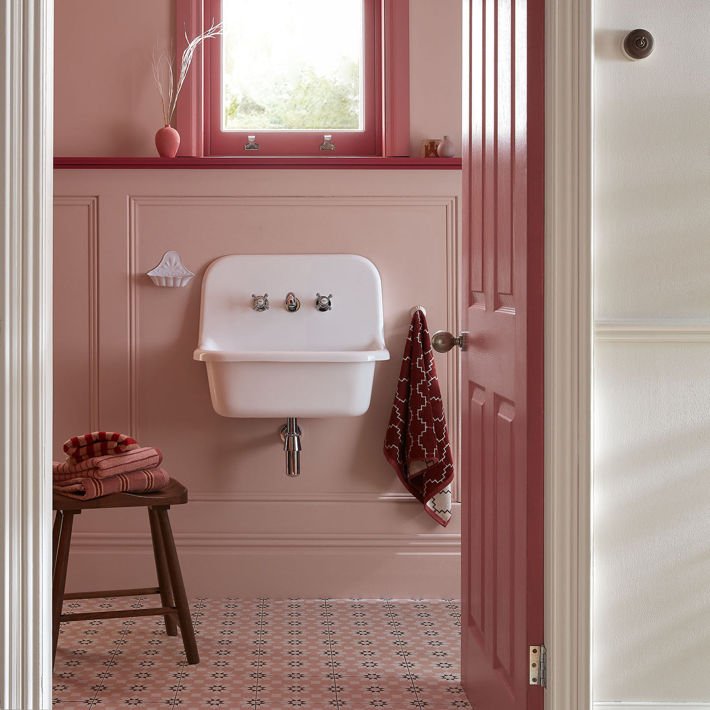 Bathroom with a white wall-mounted sink, pink walls, and patterned floor.