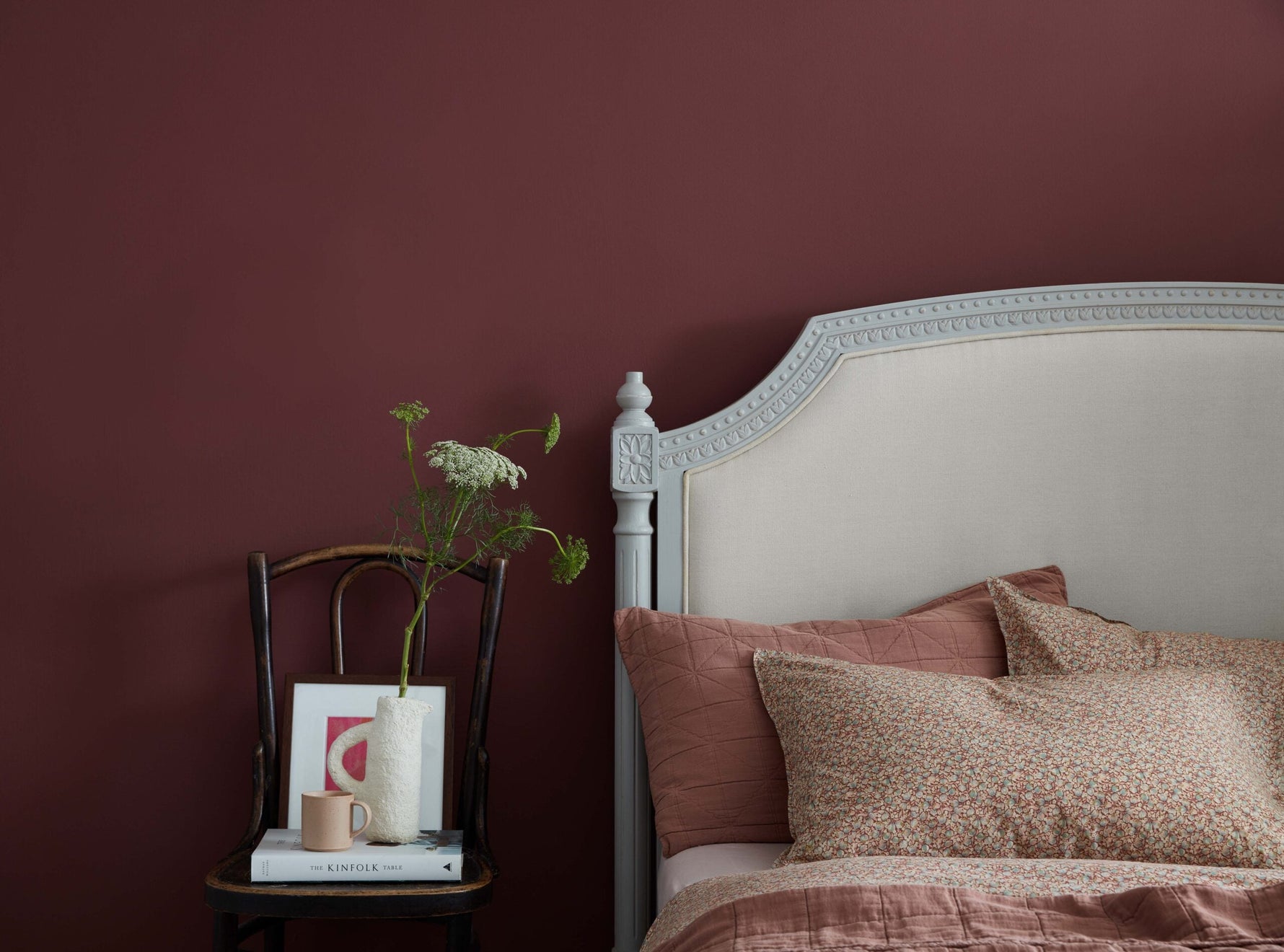 Bedroom landscape in Lady Bug Claypaint.|Kitchen illustration.|A desk and chair against a wall with a brightly coloured lamp and accessories.|A framed photo on a dual coloured wall.|A towel rack in a bathroom next to a wooden chair.|The countertop in a ki