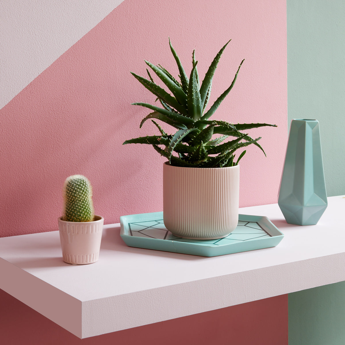 Hawaiian Tropics - Interior decorating ideas.|Bedroom layout with a pattern statement wall and large window.|Maximalist style décor of a brightly patterned wall behind a checker painted table stacked with books, candle holders and a vase of flowers.|Soft