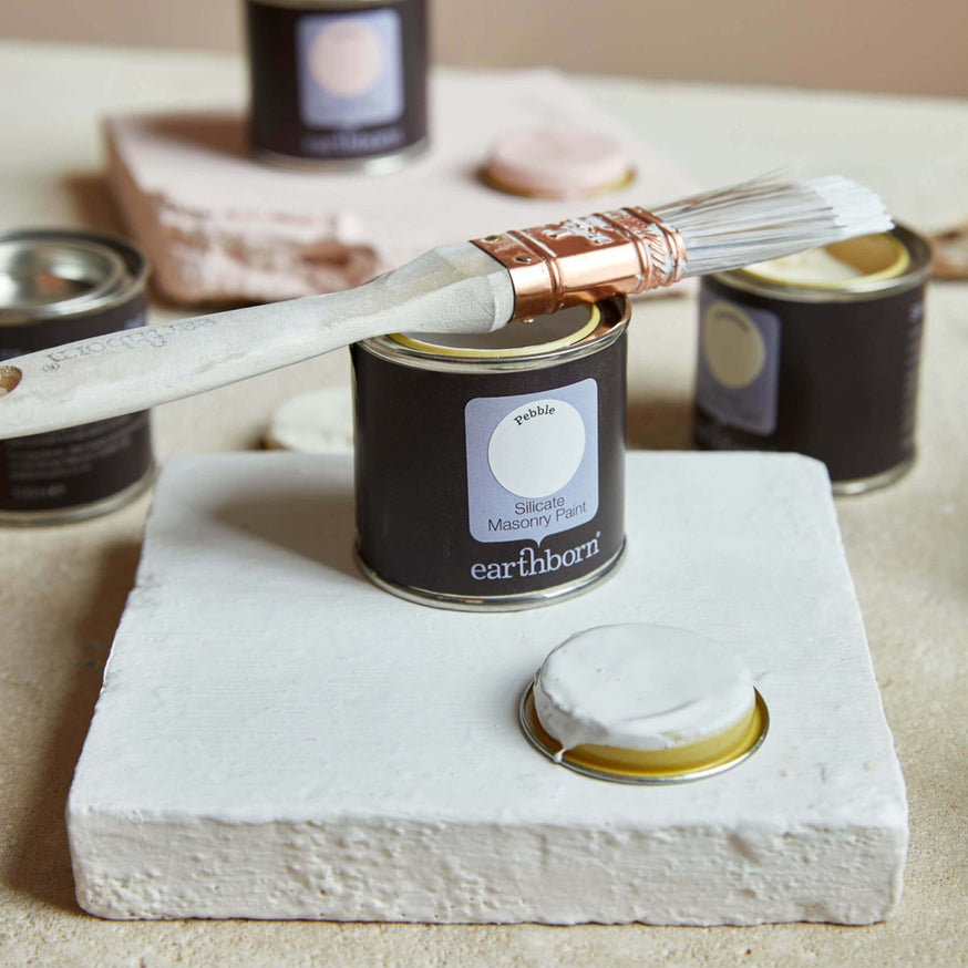 Product shot of Pebble with sample pot and paint brush. Perfect paint for listed buildings