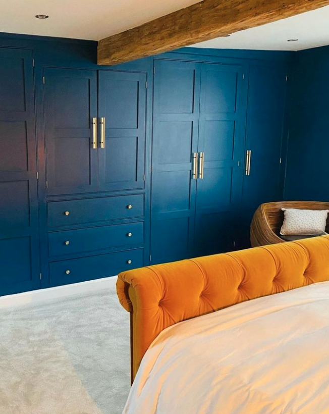 Deep blue wardrobe with a contrasting yellow bed and wooden beamed ceiling.|Beautiful blue, pink and white bedroom setting with a hint of a coastal theme.|Pale blue bedroom with wooden beams and furniture.