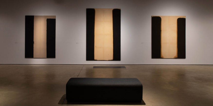 Hastings Contemporary gallery with 3 paintings hanging in a row.|Image of Yun Hyong-Keun story on a wall at his exhibition.|Yun Hyong-Keun gallery exhibition at Hastings Contemporary.|3 hanging paintings of the artist Yun Hyong-Keun on exhibit.|Painting h