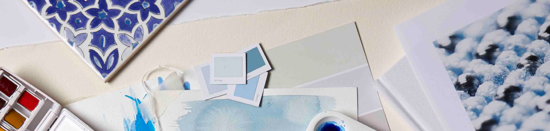 Creative mood board of different blue objects and blue colour cards.|Wooden kitchen table setting with a green wall behind that has blue panelling around a fire place. Fresh summer time.|Side profile of a stair case with vibrant blue walls, wooden furnitu