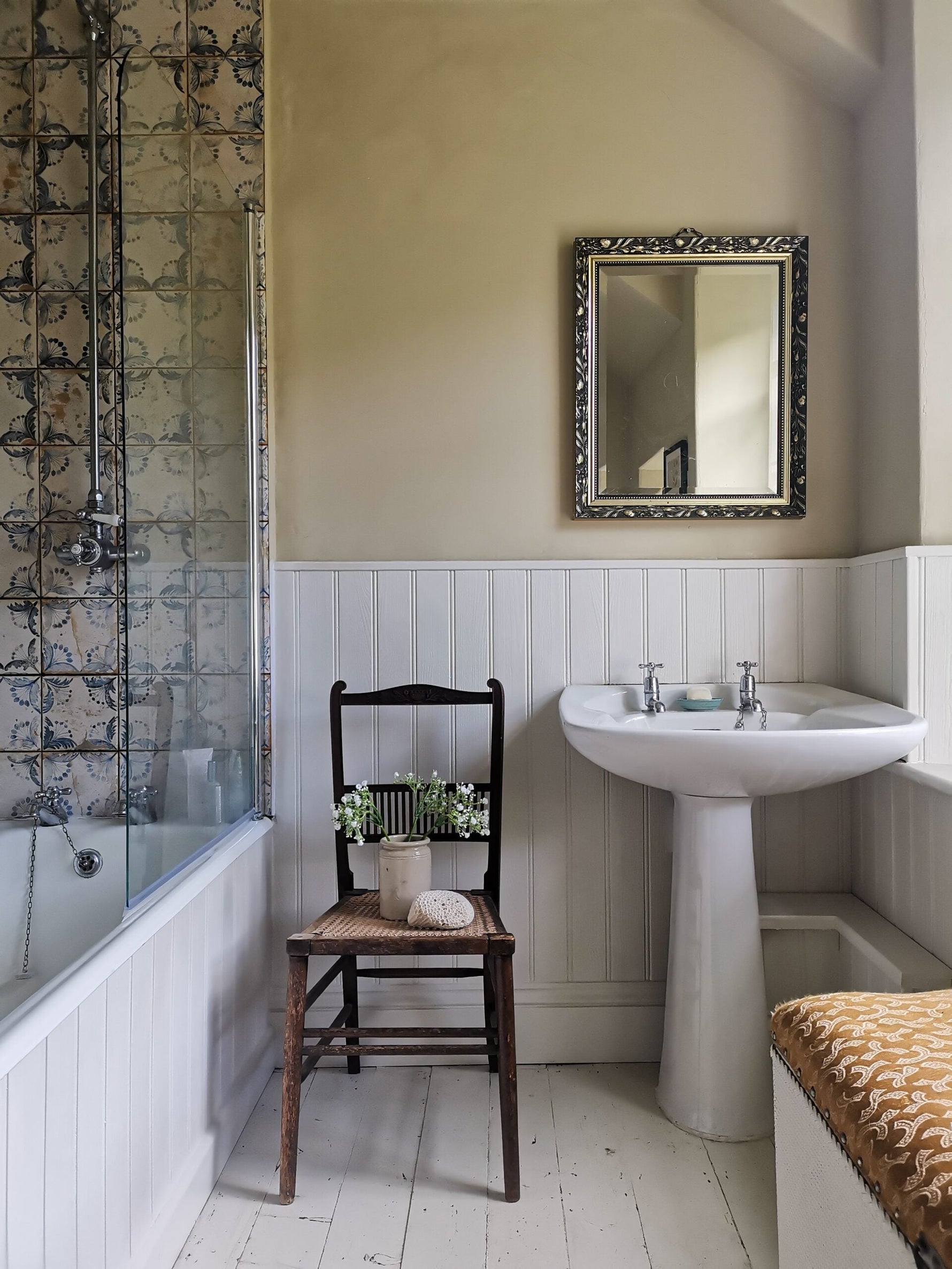 Neutral and white bathroom with blue patterned tiles.|Close up of bathroom sink and shower with a chair and some flowers and shells as decorations.|Bathroom sink in a white room with a wooden ceiling.|Olive tree in a bathroom next to the sink.|Wooden hook