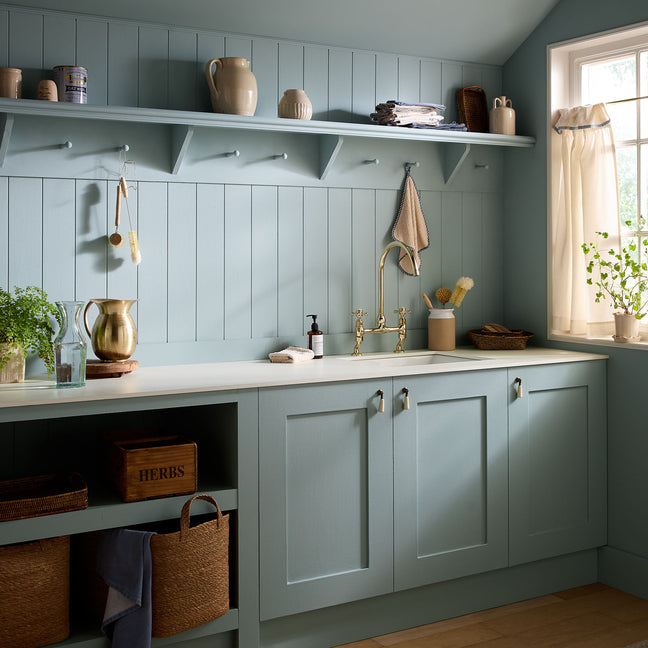 Modern kitchen with light blue cabinets, white countertops, and decorative items.