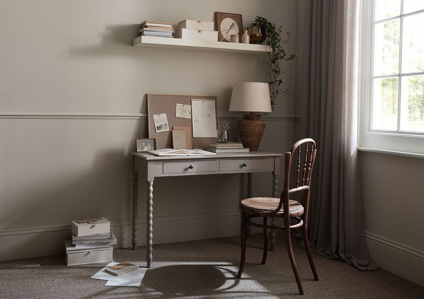 Home office with desk, chair, and shelves against a neutral wall.