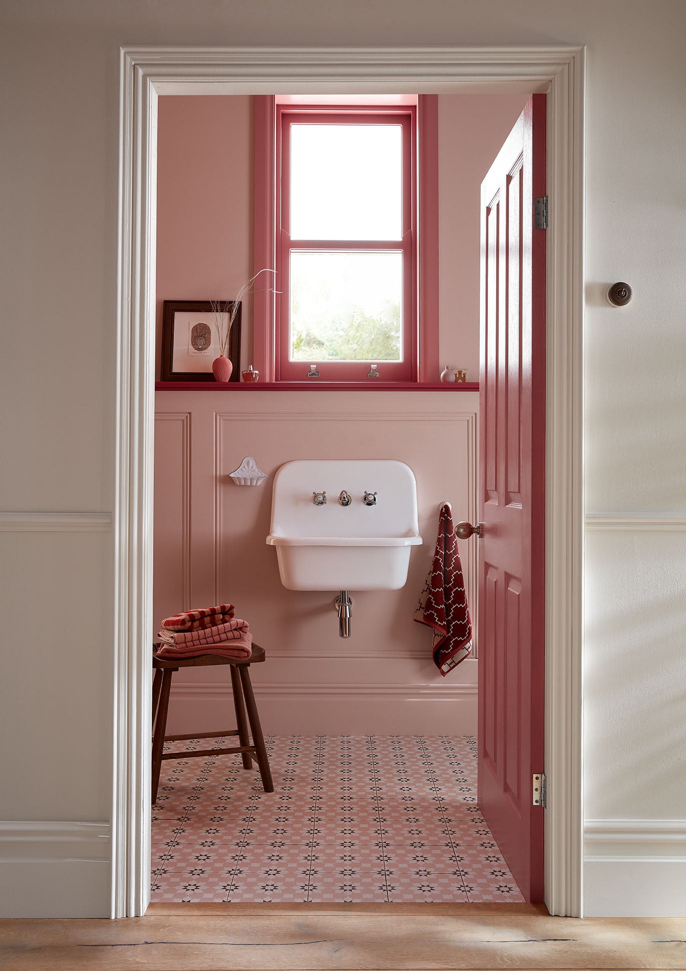 Bathroom with pink walls, white sink, and patterned tiles.
