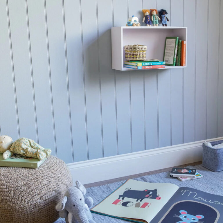 A child's room painted in pale blue and scattered with books and soft toys.