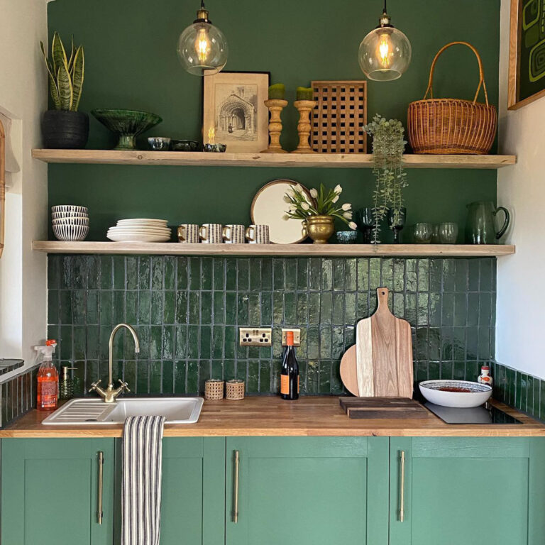 A deep green kitchen with open shelving and hanging lights.