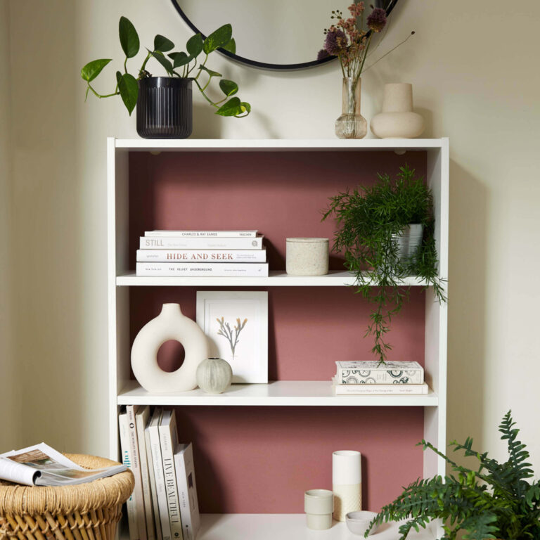 A bookshelf with green and neutral accessories.