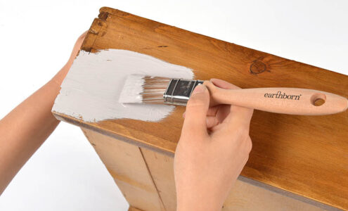 Applying paint to wooden furniture.