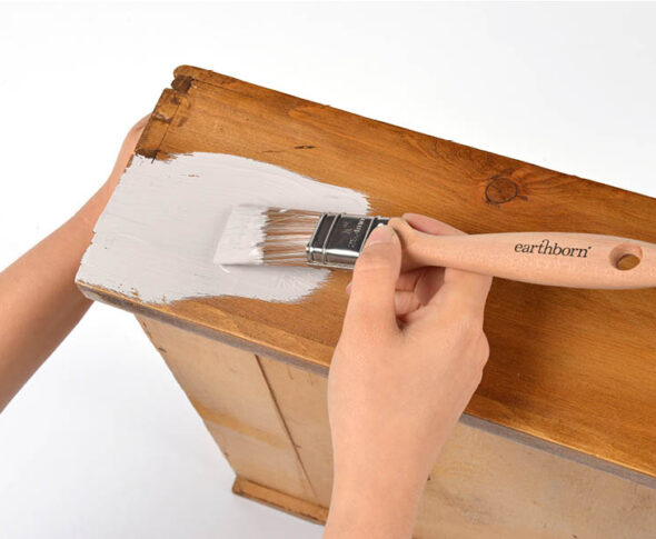 Applying paint to wooden furniture.