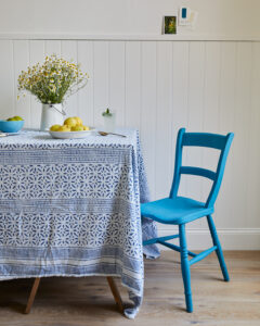 A blue painted chair in front of a white wall