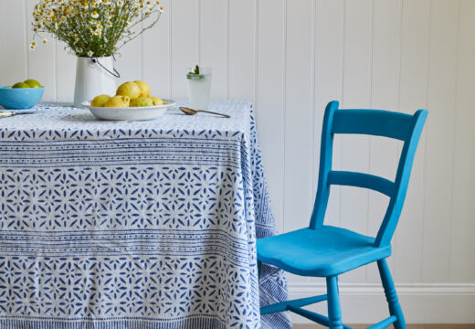 A blue painted chair in front of a white wall