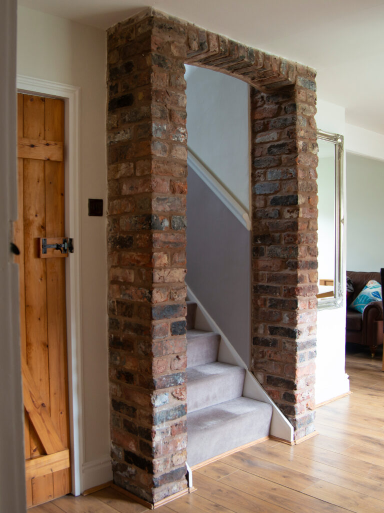 Raw brick edging around the entrance of stairs from the living room.