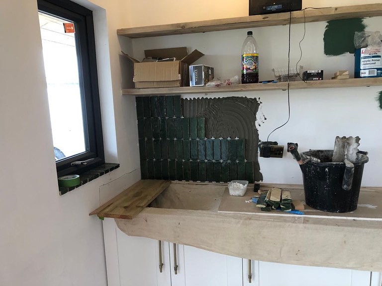 Stripped back and tiling of a wall above cupboards.