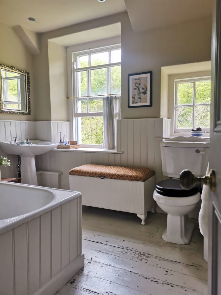 White panelled bathroom with two windows and lovely natural lighting.