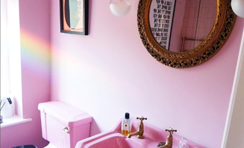 Pink bathroom with gold accents and mirror.