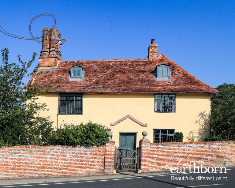 Outside view of a lovely old house with a bricked wall and garden gate.