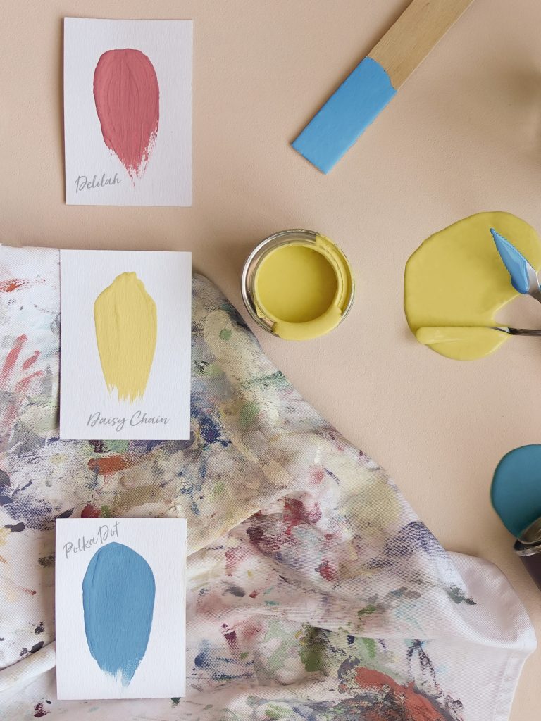 Paper swatches on a well used apron with sample pots.