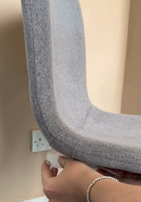 Placing masking tape around the leg of a fabric chair.
